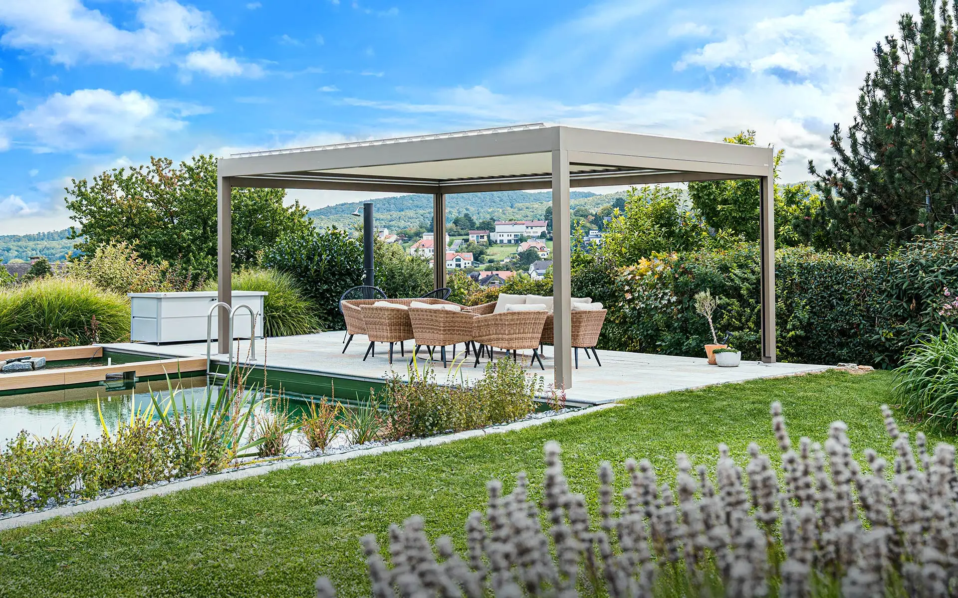 Frei stehendes Terrassendach mit Tisch und Rattanstühlen, neben einem Pool in einem schön gepflegten Garten.